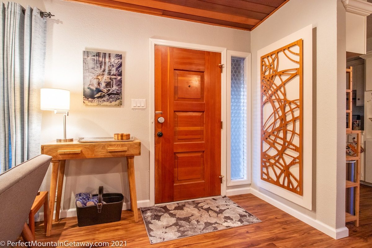 Wooden door entrance with decorative wall panel and rug.