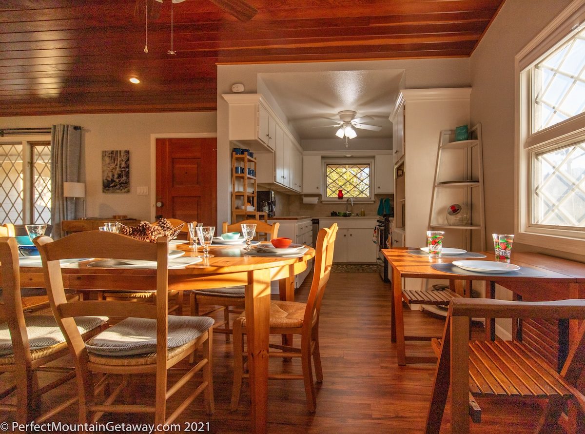 Wooden dining table with chairs in a sunlit room.